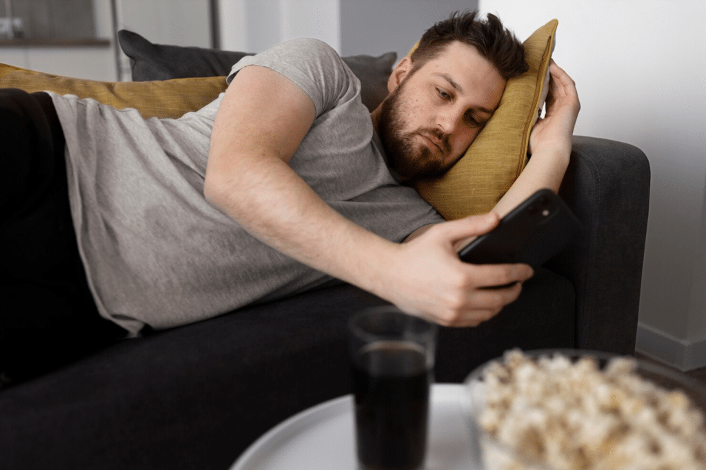 A man lying on the sofa and using a phone