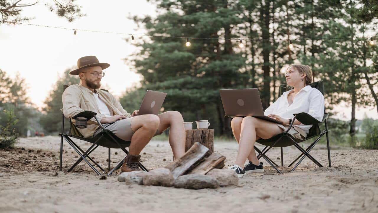 A couple sitting on folding chairs while working