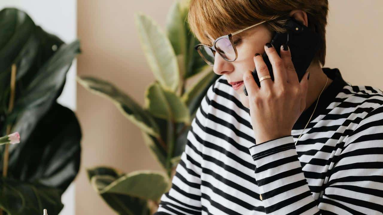 A woman wearing glasses and a striped shirt is talking on the phone