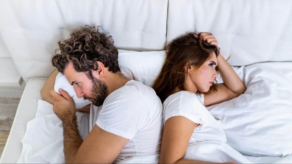 A man and woman sleeping and facing away from each other