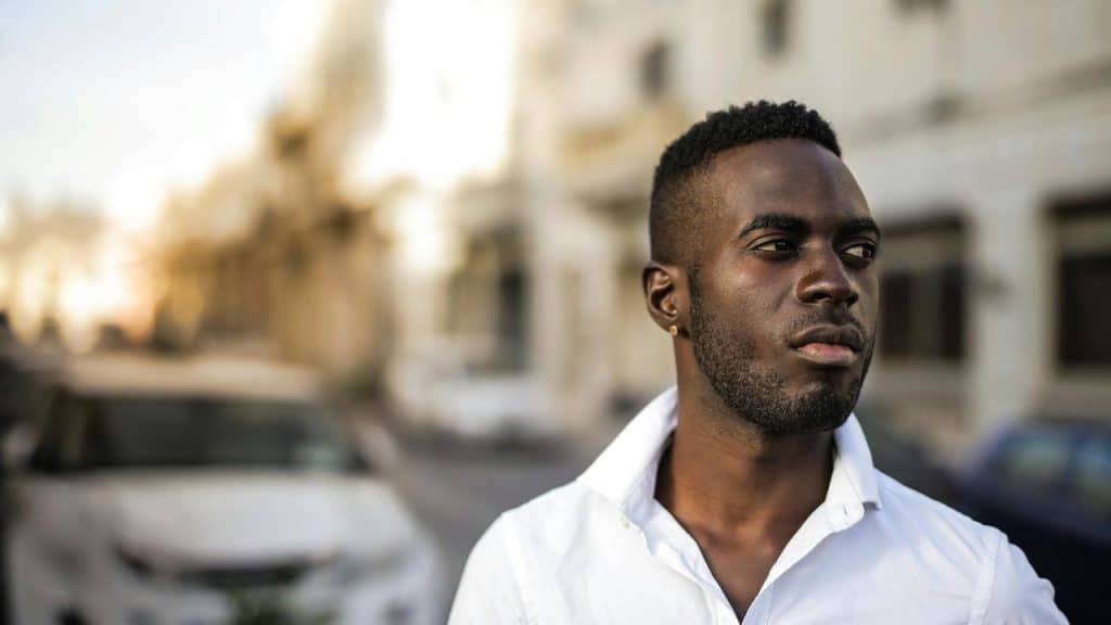 A man in a white shirt looking to the side on a city street.