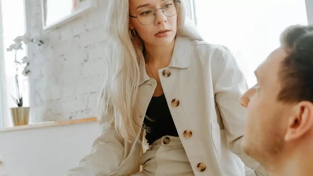 A woman wearing glasses looking down at a man with a concerned expression