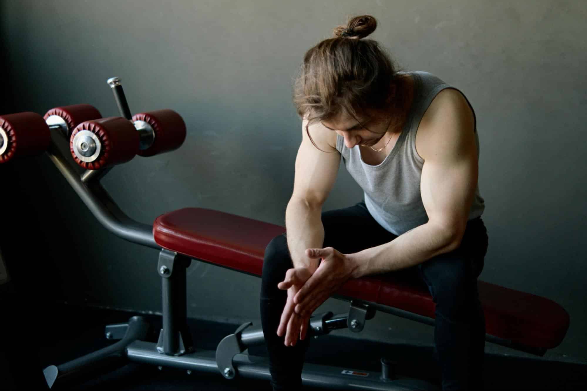 A man sitting on a workout bench.