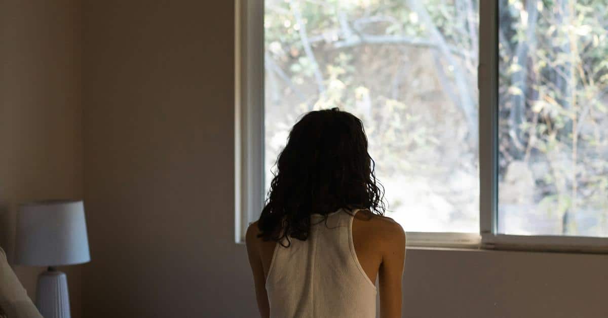 A person sitting with their back to the camera, looking out a window.