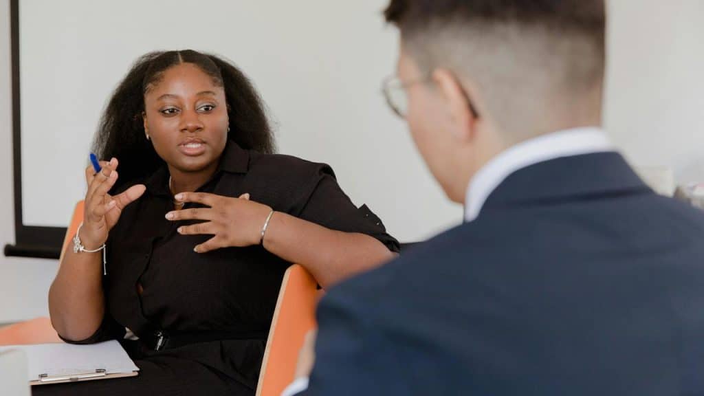 A woman gesturing while speaking to a man in a meeting.