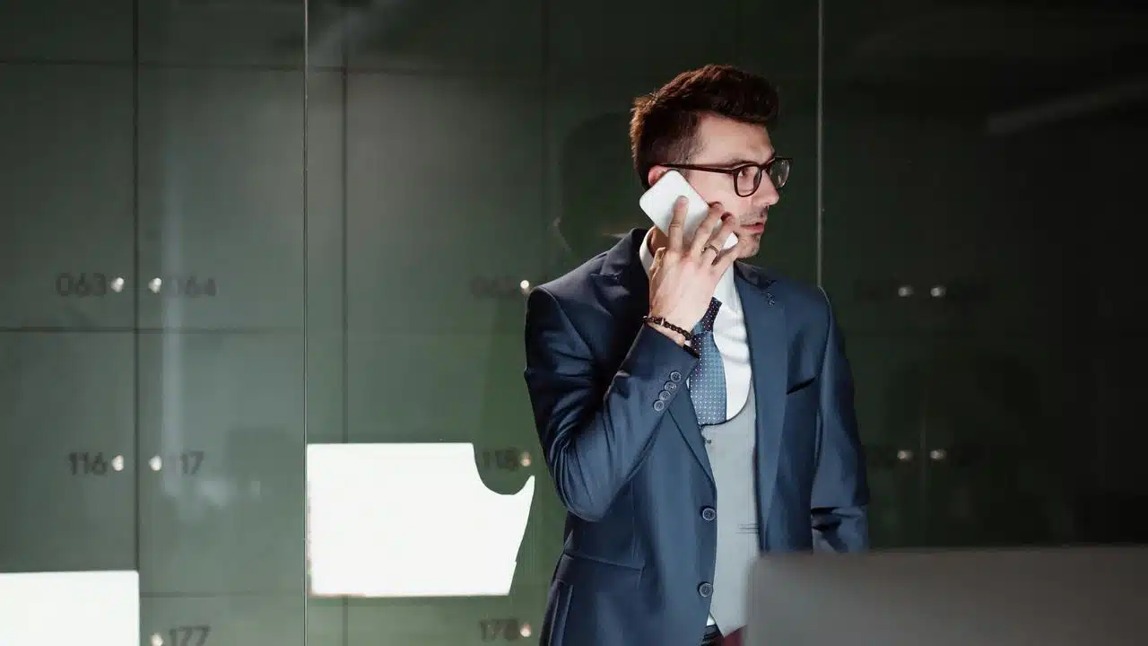 A man in a suit talking on a smartphone in a modern office.