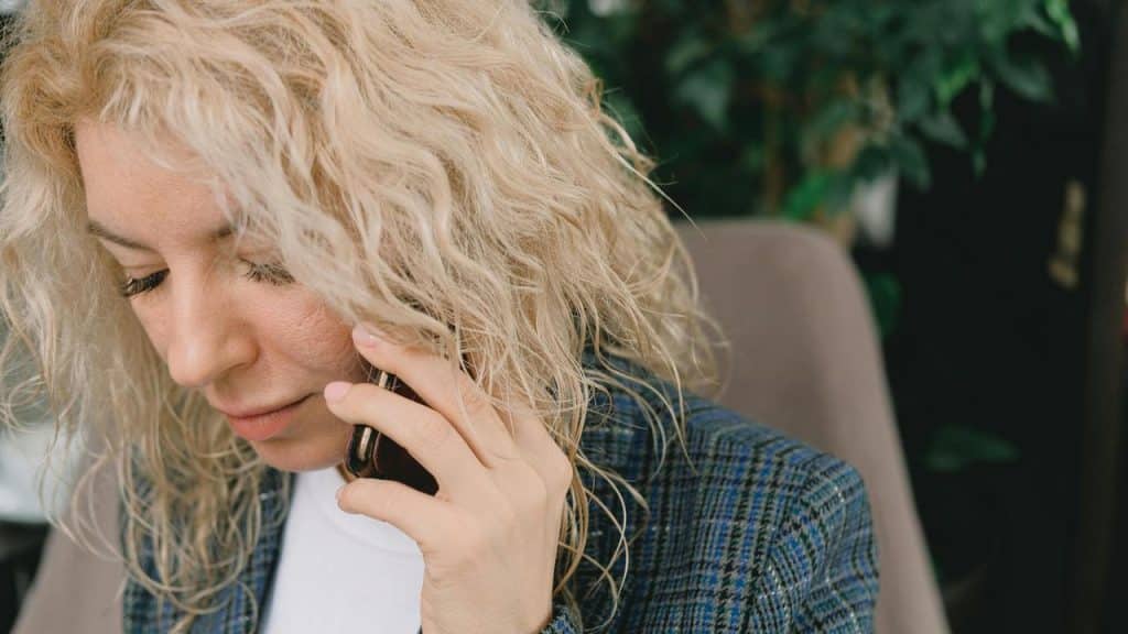 A woman with blonde hair talking on the phone.