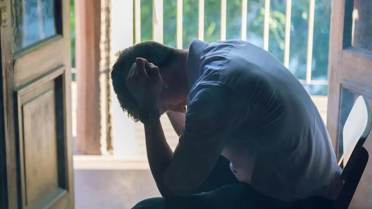 A stressed man sitting with his head in his hands.