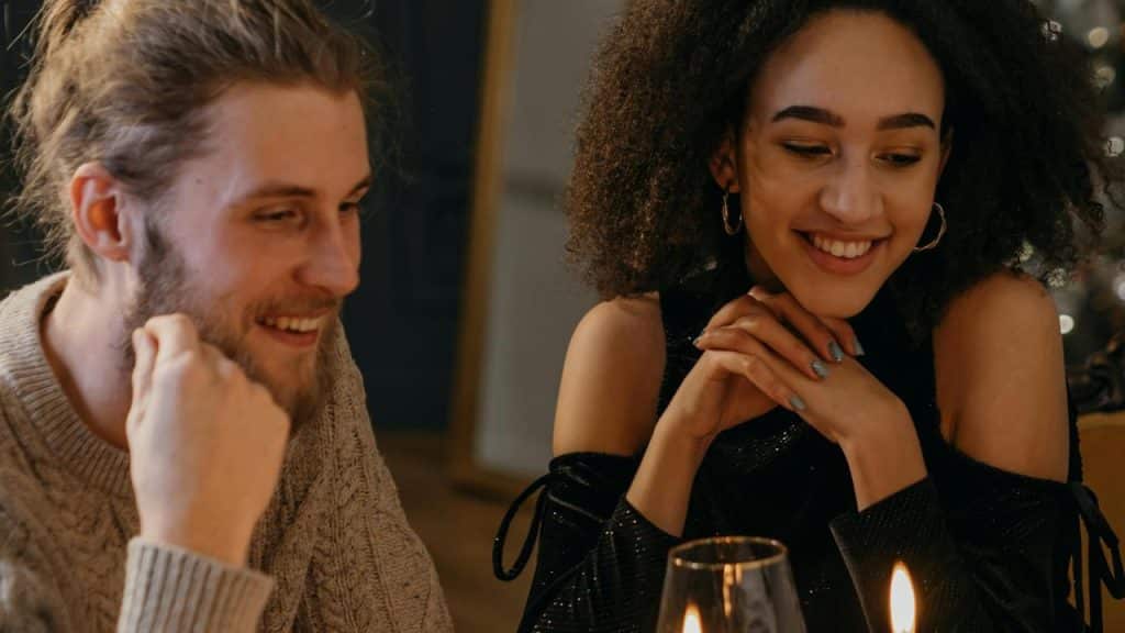 A smiling couple sitting together at a candlelit table.