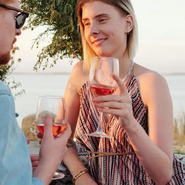 A couple enjoying a glass of wine together outdoors at sunset.