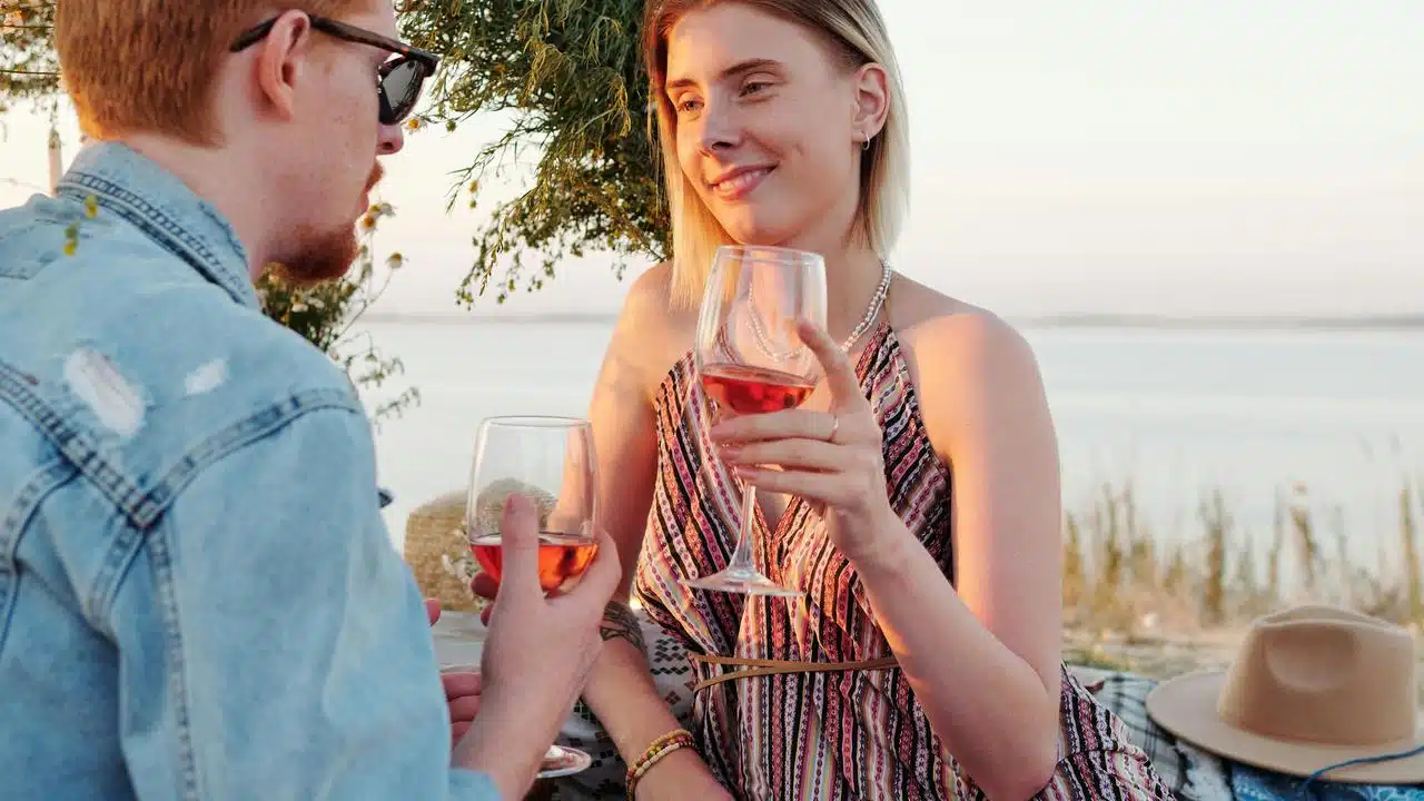 A couple enjoying a glass of wine together outdoors at sunset.
