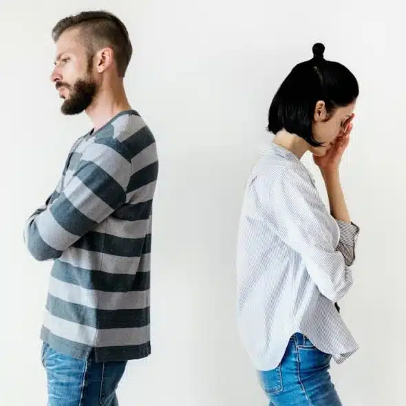 An upset couple standing with their backs against each other.