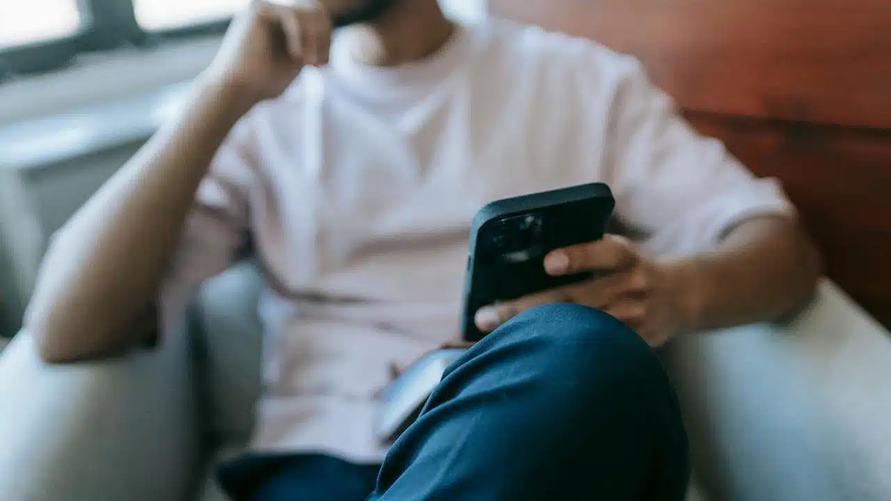A person sitting and looking at a smartphone.