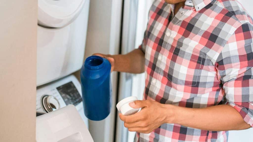 A person pouring laundry detergent into a washing machine.