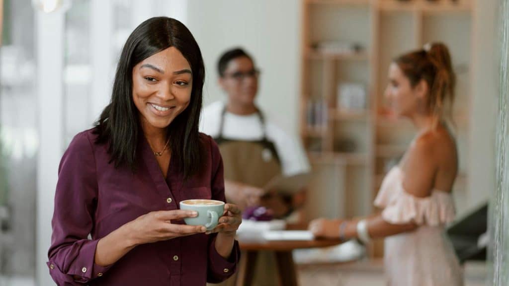 A smiling woman holding a cup of coffee in a café.