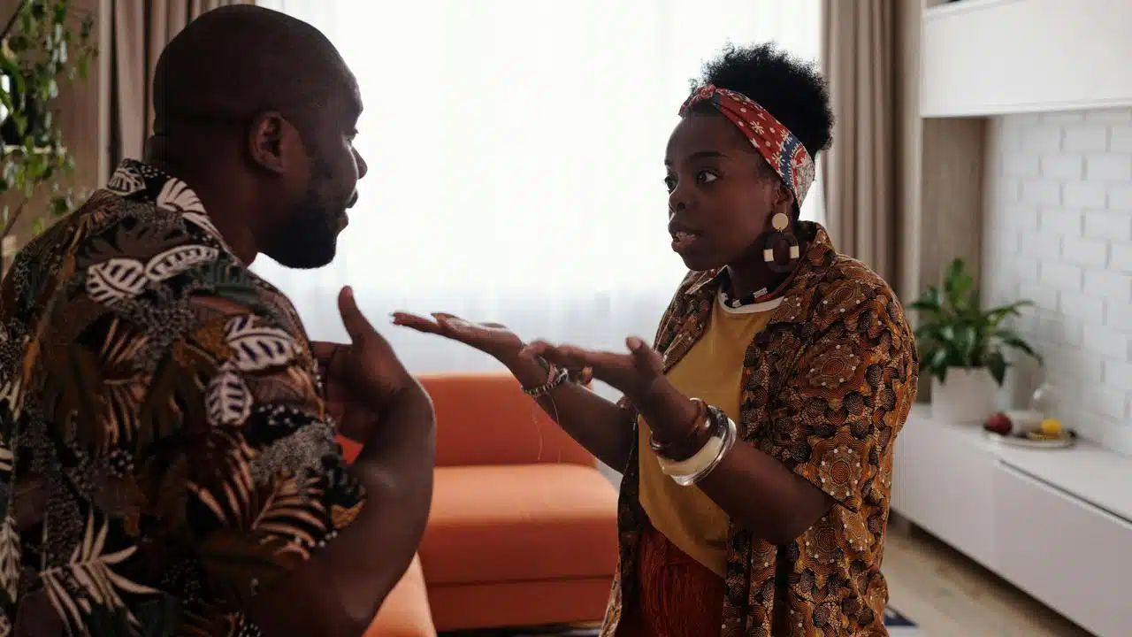 A woman gesturing while arguing with a man in a living room.