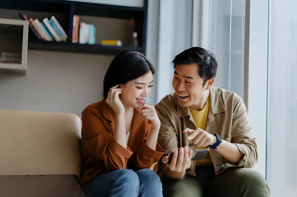 Couple in living room looking at phone smiling