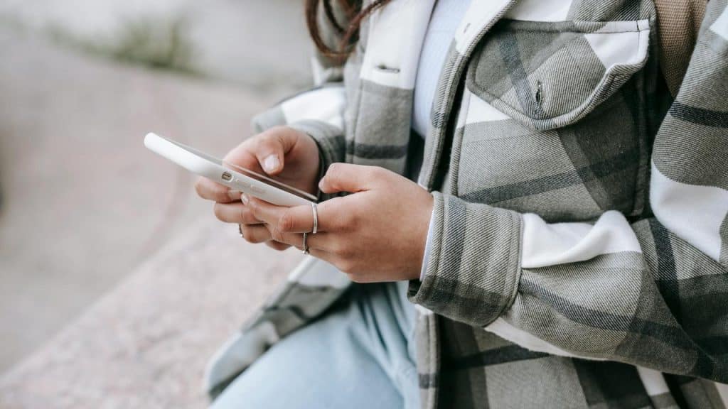 A person holding and using a smartphone outdoors.