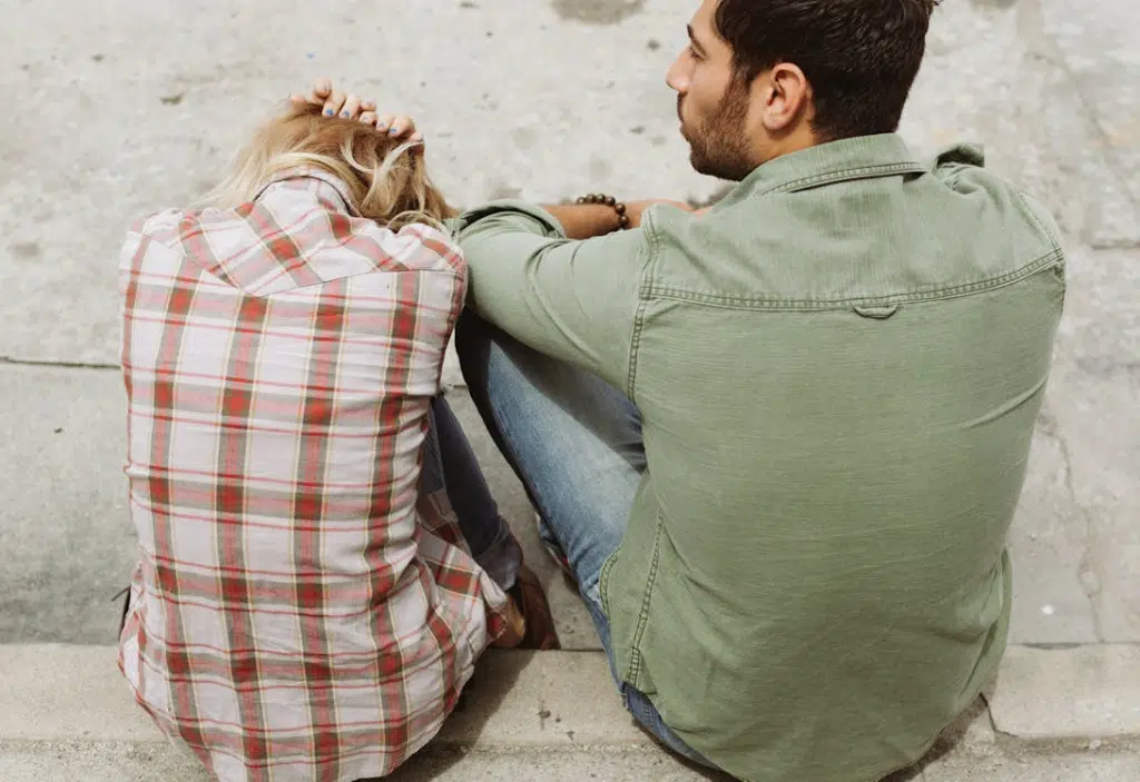 Unhappy couple sitting and woman cowering in fear