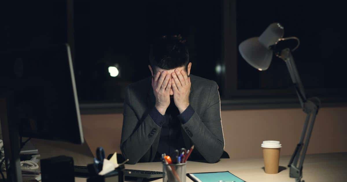 A man sitting at a desk covering his face