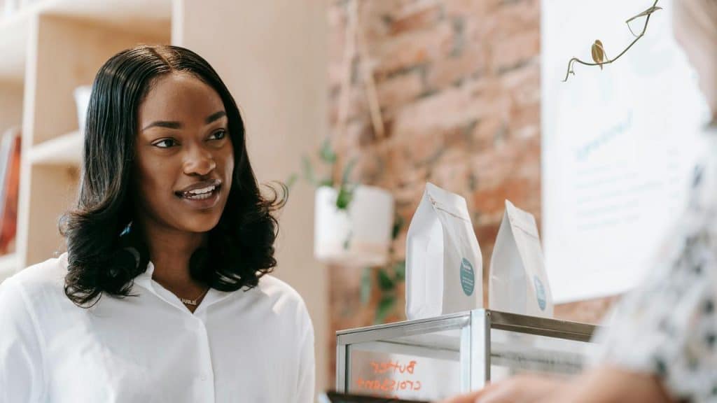 A woman smiling while speaking to someone at a counter in a shop.