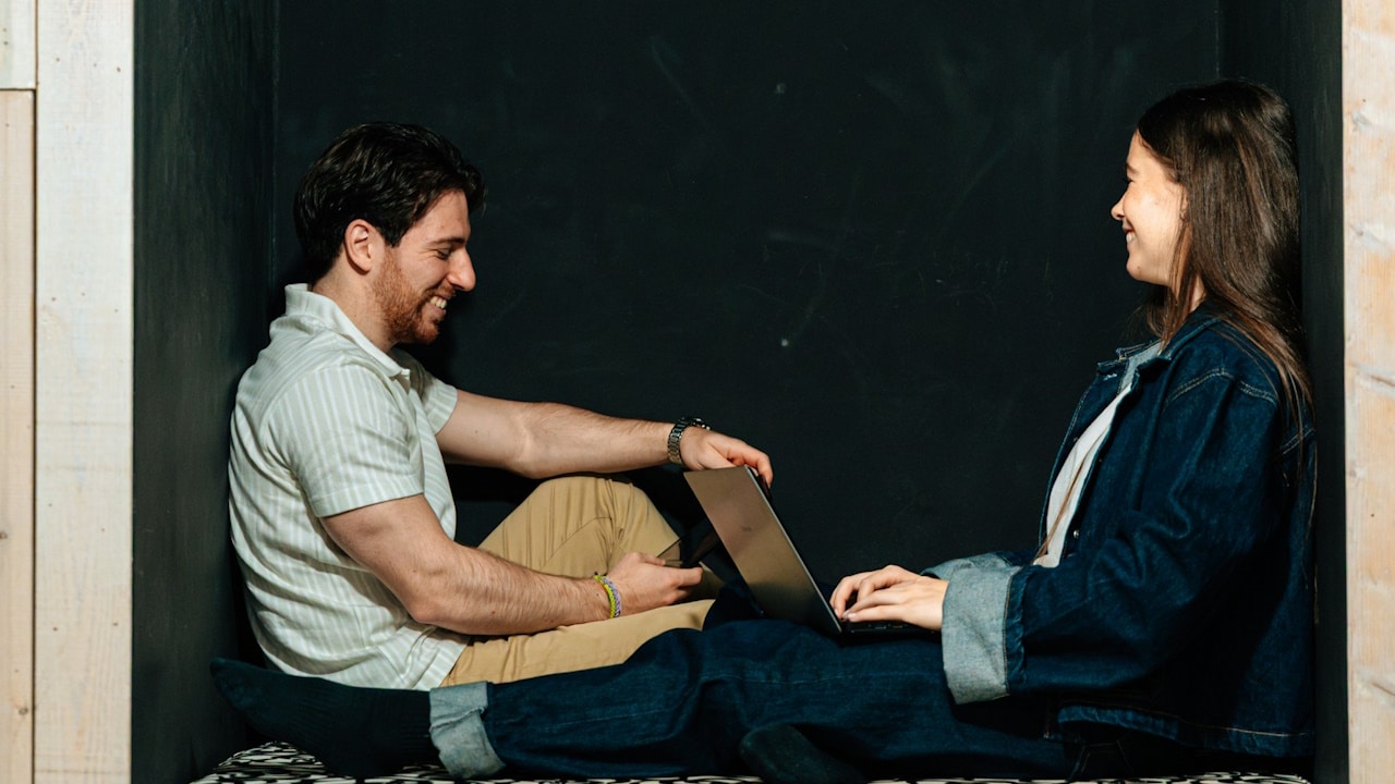 Two people sit inside a niche, smiling.