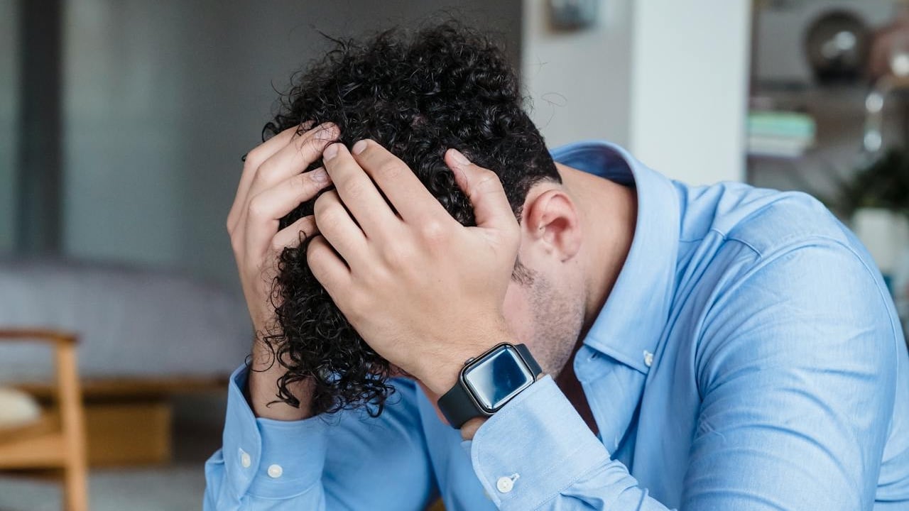 A man holding his head in stress while sitting down.