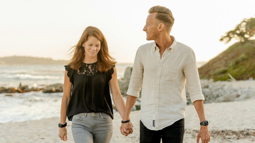 A man and woman are standing on the beach during the daytime.