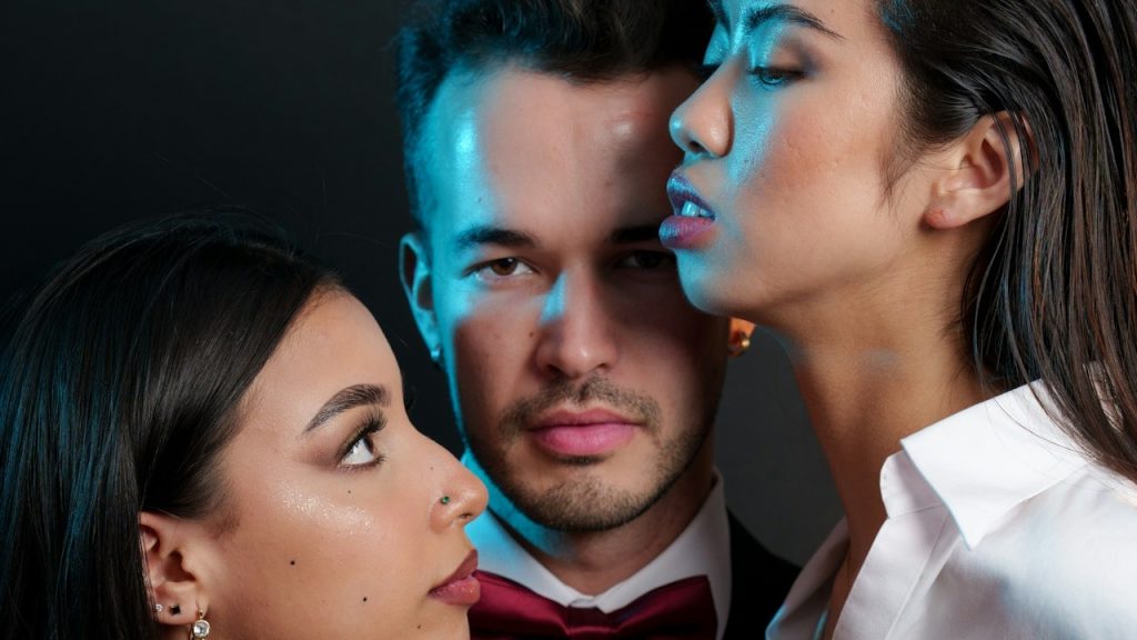 A man standing close to two women.