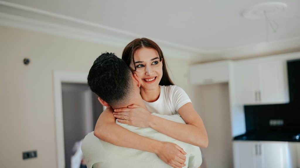 A woman hugging a man in a living room.