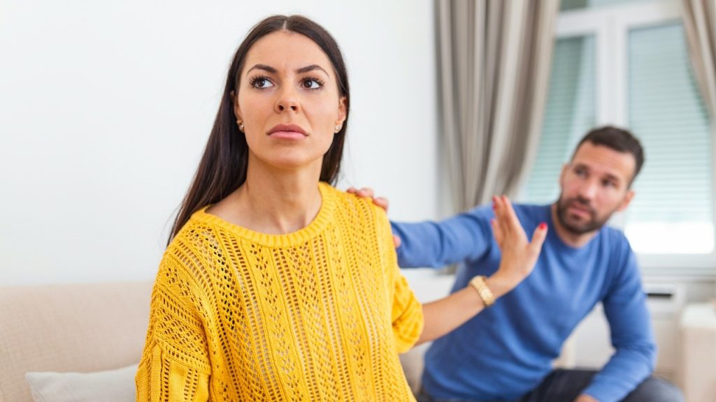 A man is apologizing to his angry wife, who is ignoring him.