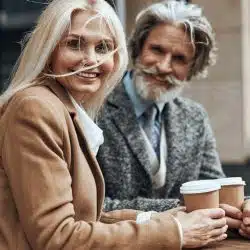 A gladsome woman turning and smiling while standing with a man at the cafe table.
