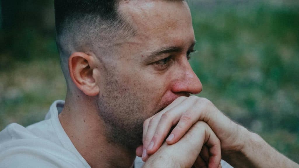 A man resting his hands near his mouth, looking worried and deep in thought.