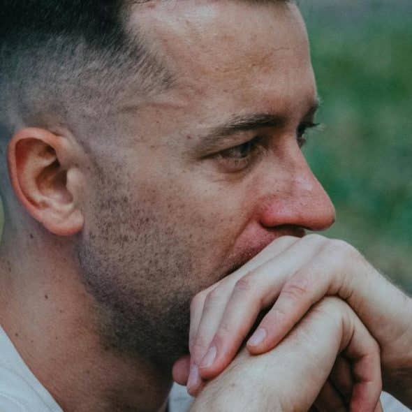 A man resting his hands near his mouth, looking worried and deep in thought.