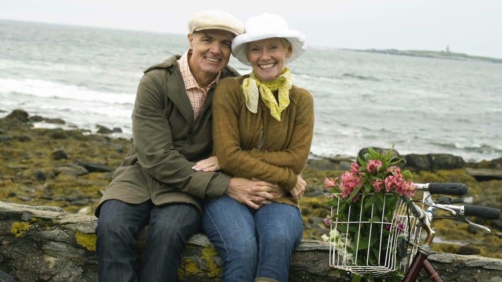A man and woman sitting on a rock next to a bike.