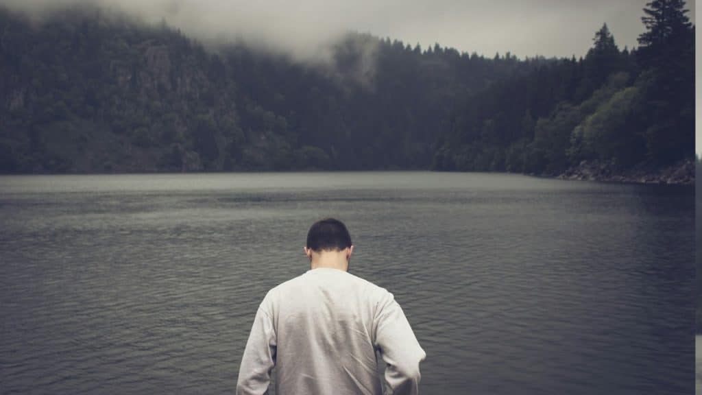 A man is standing near a body of water.