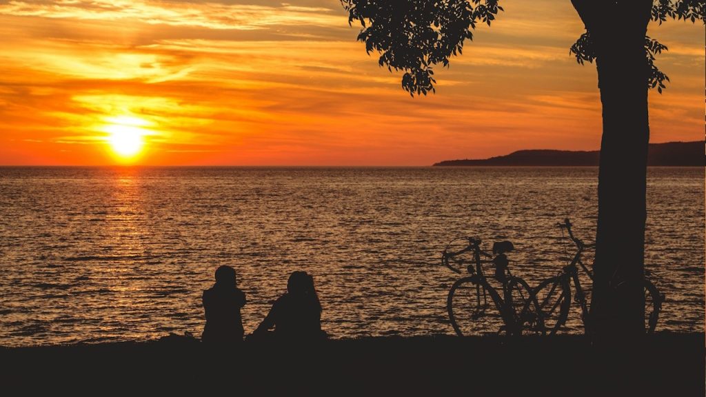 A silhouette of a couple sitting by the sea and having a conversation at sunset.
