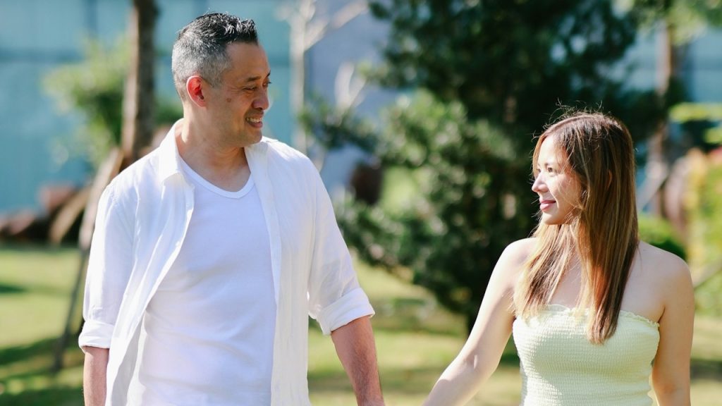 A couple looking in each other's eyes and holding their hands while walking in a park.