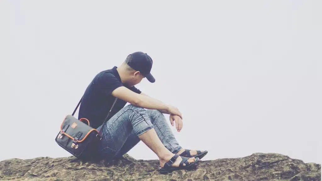 A man sitting on the rocks with his face turned away.