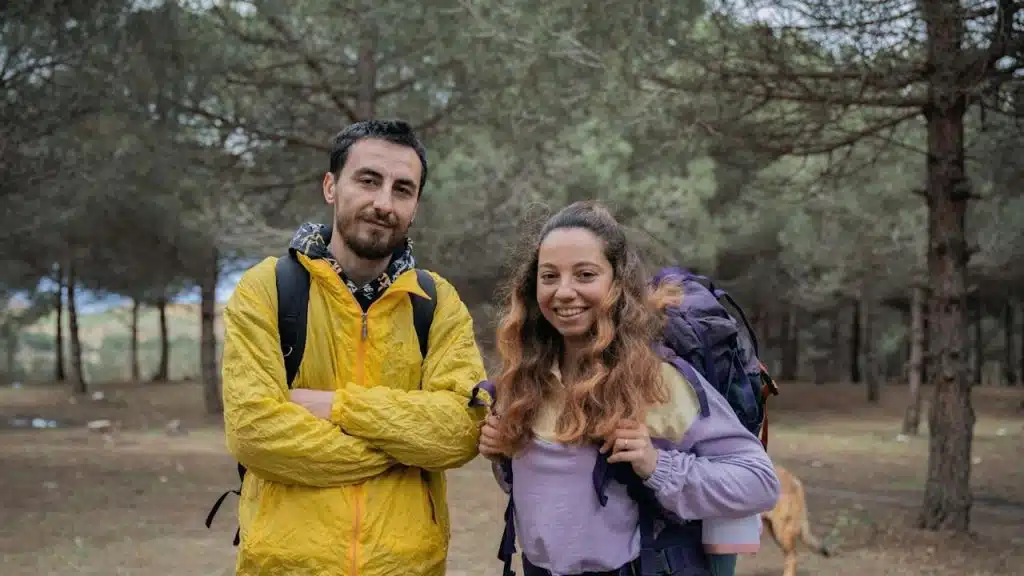 A man and a woman standing in a forest.