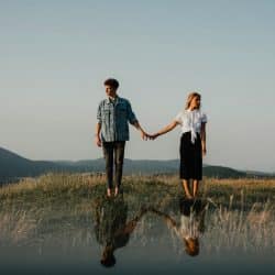 A couple holding hands but looking away from each other.