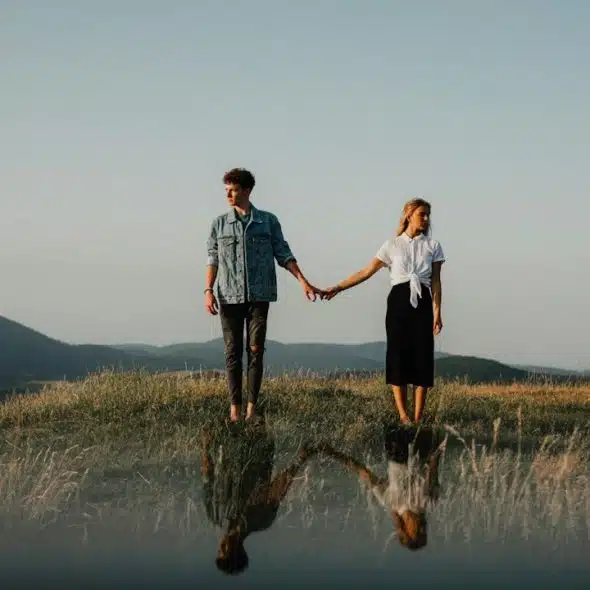 A couple holding hands but looking away from each other.