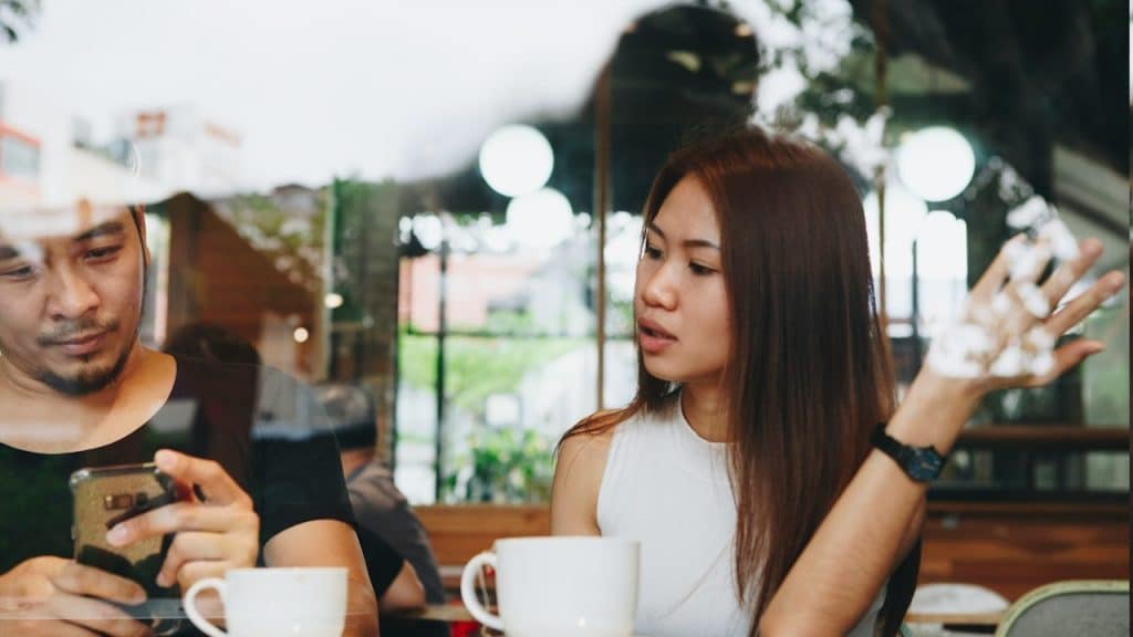 A woman is talking but her husband is using his phone and ignoring her completely.