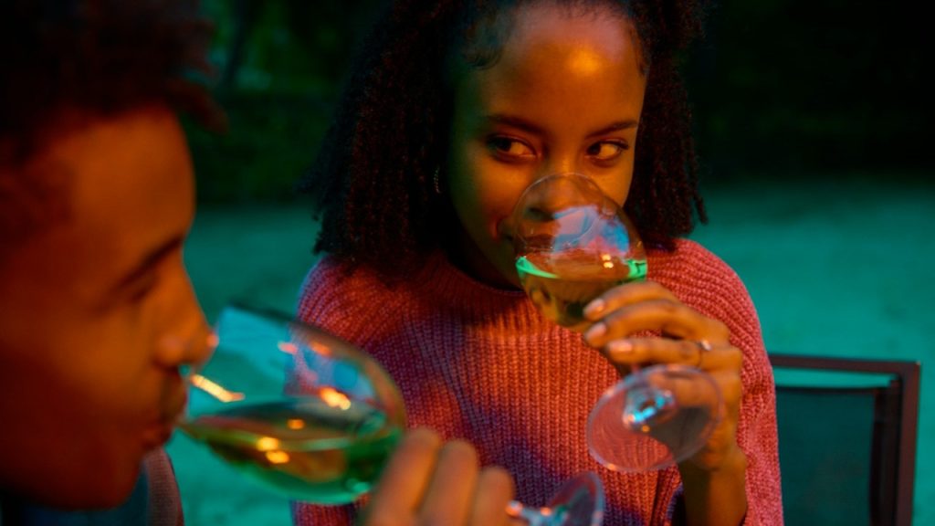 A woman looking at her boyfriend while they are having wine together.