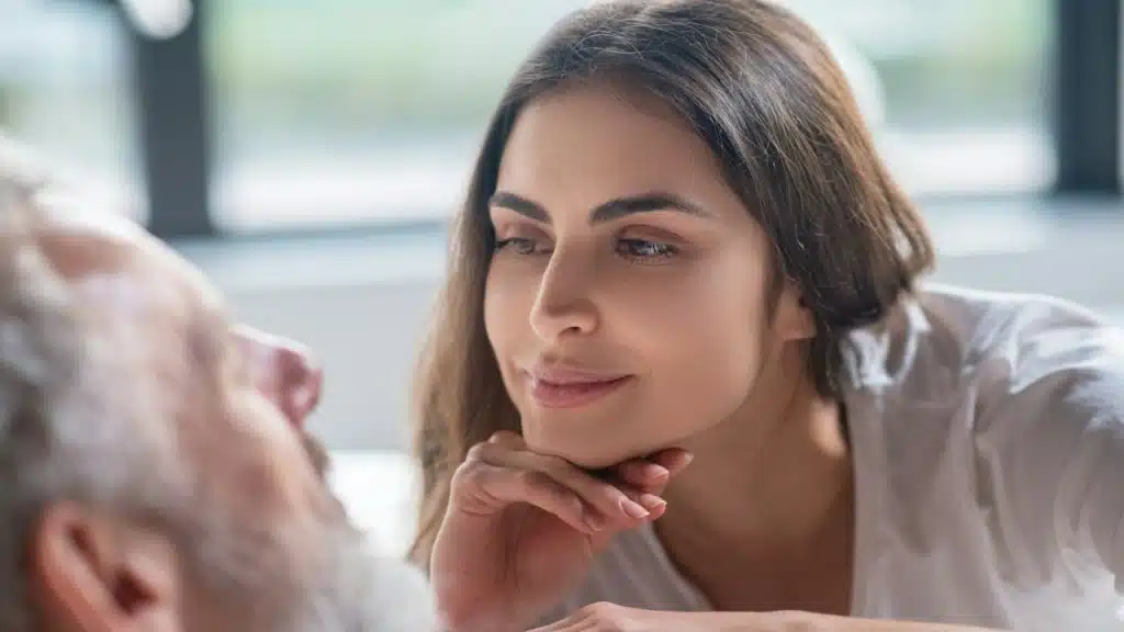 A woman looking in the eyes of her man while sitting close to him.