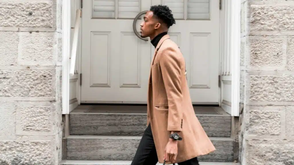 A man wearing a coat walking down a street.