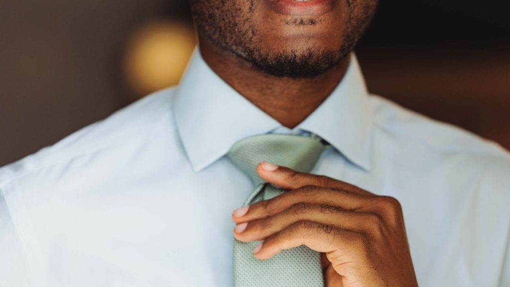 A close-up of a confident professional adjusting tie.