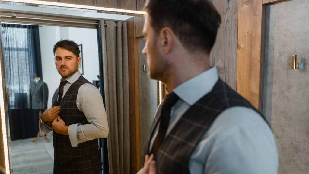 A man in a suit looking at his reflection.