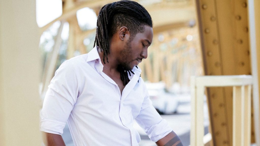 An elegant African man standing on a bridge.