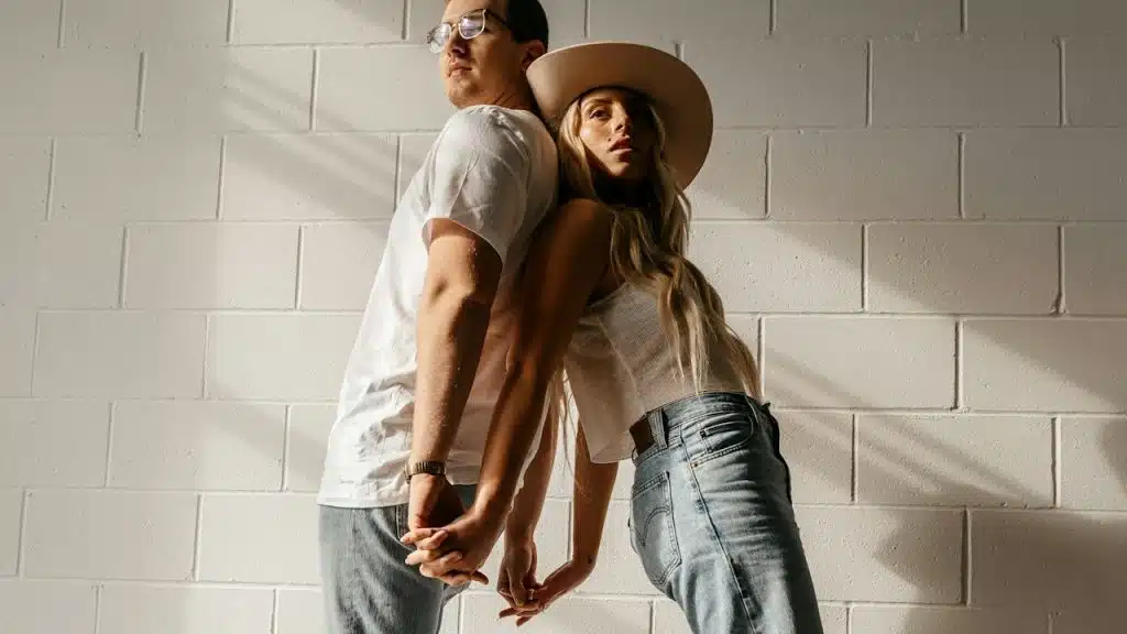 A man and a woman standing in front of a brick wall.